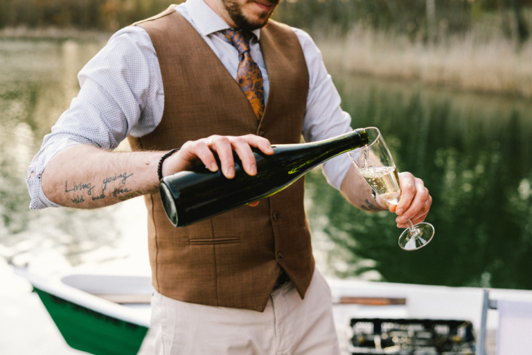 Sommelier nalewa wino nad jeziorem